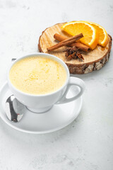 Morning cappuccino with orange flavor in a white mug on a white background.