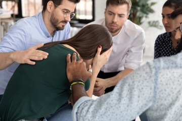 Overcoming crisis. Crying millennial female having personal problems taking part in group therapy session receiving support understanding from diverse participants and professional psychological help