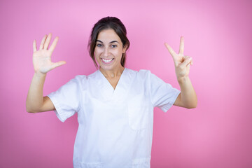 Young brunette doctor girl wearing nurse or surgeon uniform over isolated pink background showing...