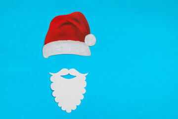 Santa Claus hat and beard on light blue background. Christmas and New Year concept.