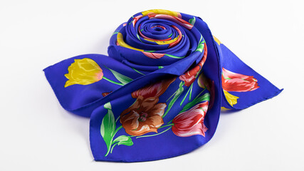 Isolated beautiful  bright  blue silk scarf with wonderful floral pattern folded nicely  is on the white background.