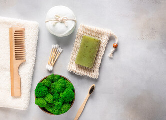 Zero waste concept. reusable cotton pads, natural herbal soap, soap saver, wood comb, cotton swabs, bamboo toothbrush and stabilized moss in pot. gray background, copy space.