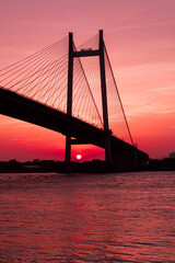 Fototapeta na wymiar An image of sunset by the Ganges, also known as Ganga in Kolkata with the famous Vidyasagar Bridge in frame