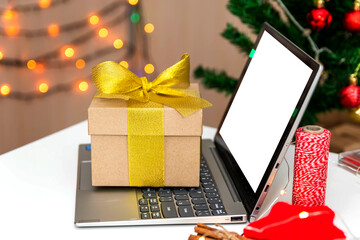 Concept of online shopping for a gift for Christmas and New Year. A box with a gift ribbon on a computer.