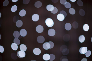 beautiful black and white festive bokeh background made up of white out of focus lights on dark background