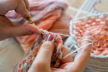 Female hands knitting with multi colored wool, top view.