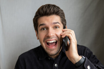 Portrait of a young cheerful man receiving a great news on his mobile phone with a happy expression on his face 