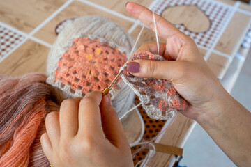 Female hands knitting with multi colored wool, top view.