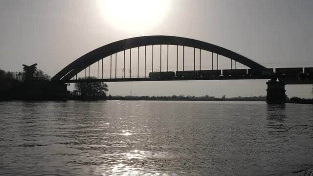 Cargo train driving over Culemborg bridge in the Netherlands, silhouette shot