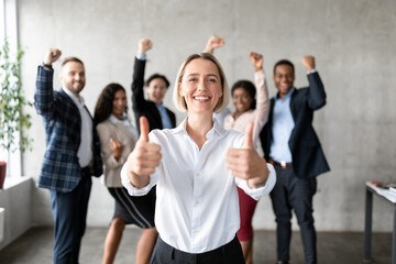 Businesswoman Gesturing Thumbs-Up Standing With Joyful Employees Team In Office - obrazy, fototapety, plakaty