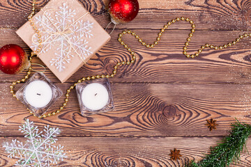 Christmas and New Year holiday background. Decor with gifts wrapped in kraft paper, candles, Christmas decorations, beads, snowflakes, on a wooden table. Flat lay, empty space