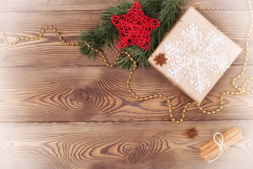 Christmas and New Year holiday background. Decor with gifts, fir branches, cones, star, beads, snowflakes, cinnamon sticks on a wooden table. Flat lay, empty space