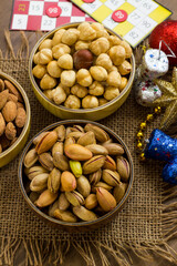 Mixed,crispy, dry nuts in bamboo bowls on wooden table,with jute napkin and christmas ornaments