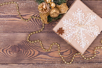 Christmas and New Year holiday background. Decor with gifts, fir branches, cones, Christmas decorations, beads, snowflakes, cinnamon sticks on a wooden table. Flat lay, empty space
