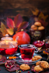 Glass cup of hot red tea and fresh homemade delicious apple cookies on rustic autumn background
