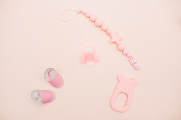 On a pink background, children's shoes, a pacifier, a bottle and a toy for a girl. Beautiful accessories for a newborn. baby products for girls, happy motherhood and childhood concept. Newborn baby 