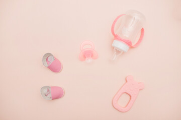 On a pink background, children's shoes, a pacifier, a bottle and a toy for a girl. Beautiful accessories for a newborn. baby products for girls, happy motherhood and childhood concept. Newborn baby 