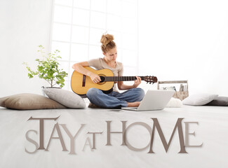 young woman with computer play guitar, look laptop monitor, with stay at home text isolated on white floor background, stay at home social media campaign for coronavirus covid-19 prevention