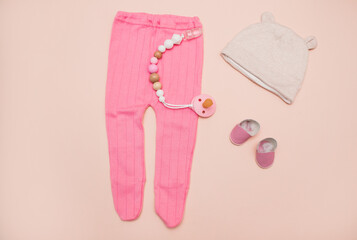 Clothes for a newborn girl: a tiny pink hat, cotton pants on a light background. baby clothes on the table. Children's fashion. clothes for newborns for girls. modern kids clothing store top view