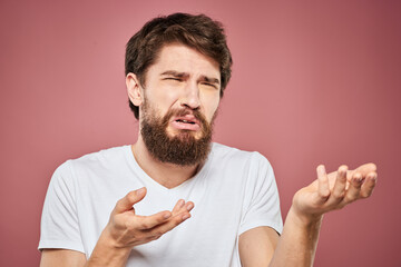 Emotional bearded man in white T-shirt discontent pink background