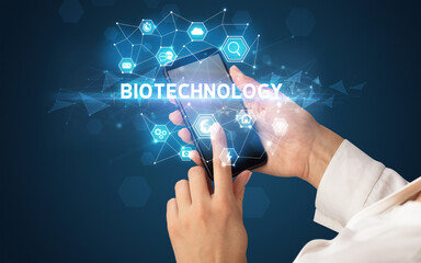Female hand holding smartphone with BIOTECHNOLOGY inscription, modern technology concept