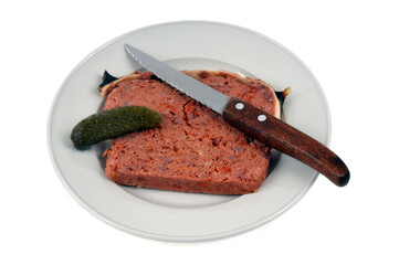 Morceau de pâté de campagne avec un cornichon et un couteau dans une assiette sur fond blanc