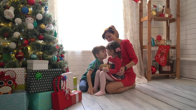 Happy family and Merry Christmas. Mother and her kids at Christmas morning at xmas tree