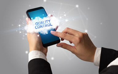 Female hand touching smartphone with QUALITY CONTROL inscription, cloud business concept