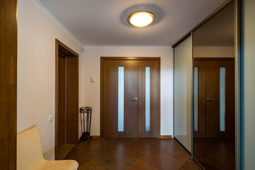 Modern interior in brown colors of entrance hall. Tiled floor. Sliding door wardrobe with mirror....