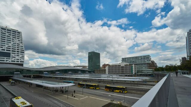 Utrecht, Netherlands - June 12 2020: 4k time lapse of the Utrecht central station with busses and trains arriving and departing on a sunny day with thick white clouds rolling by