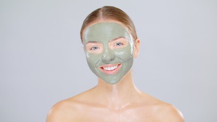 Close-up Beauty Portrait Of Young Caucasian Blonde Woman She Have Green Mask On Face And Smiling On Gray Background Skin Care Cosmetic Concept