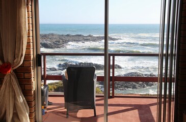 Fototapeta na wymiar Balcony and chair, in front of the wild atlantic ocean. Yzerfontein, South Africa, Africa.
