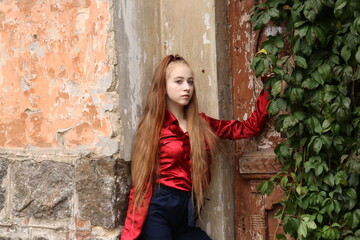 girl in red clothes in a green leaf near the old house