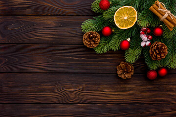 Fototapeta premium Spruce branch, cones and toys decoration on christmas or new year on dark wooden background.