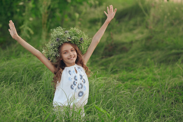 Naklejka na ściany i meble Cute little girl wearing wreath made of beautiful flowers in field