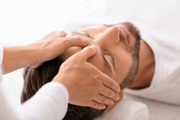 Peaceful man getting healing head massage at spa - Powered by Adobe