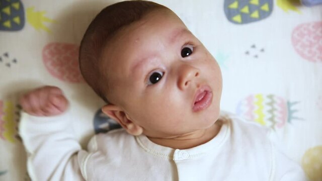 A nice little caucasian newborn baby is funny smiling, Portrait of a playful and energetic child close-up.