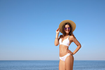 Young woman with beautiful body on beach. Space for text