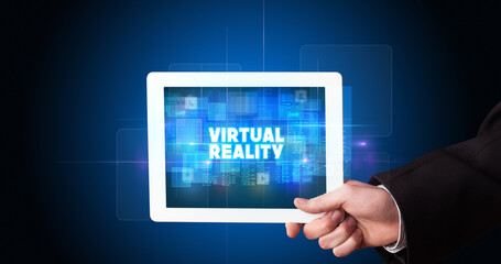 Young business person working on tablet and shows the inscription: VIRTUAL REALITY