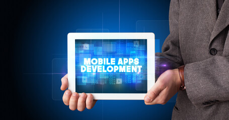 Young business person working on tablet and shows the inscription: MOBILE APPS DEVELOPMENT