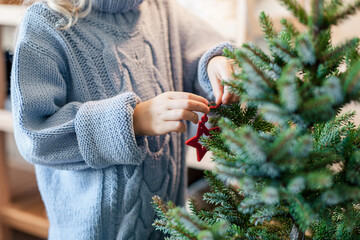 Kid decorating Christmas tree at home. celebration in cozy holiday atmosphere during quarantine....