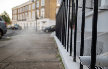 Steam appearing from a external building pipe at from a low level with background of blurred out row of Georgian houses on London street.