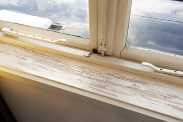 Old wooden window sill with cracked peeling paint and durt, needs renovation and repaired, replaced
