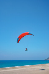 Paraglider tandem flying over the sea shore with blue water and sky on horison. View of paraglider and Blue Lagoon in Turkey. Extreme sport. Landscape