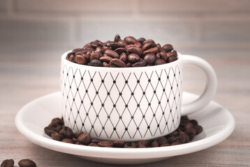 The white Cup is filled with roasted coffee beans. Side view. Concept of coffee backgrounds.