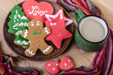 Christmas gingerbread cookies and a mug of hot chocolate on a light wooden top.