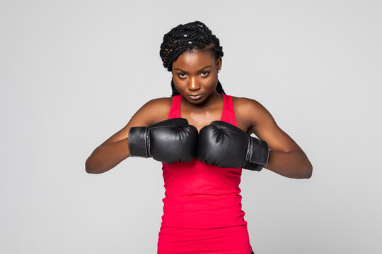 Portrait of beautiful black woman boxer in fighting gloves on gray background.