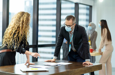 Group of corporate colleagues wearing protective medical face mask for health, in formal suit, discussing of work in the modern office. health, businesspeople and office concept