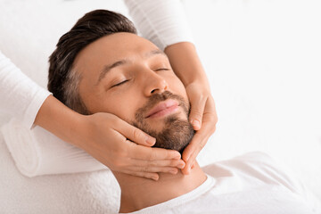 Spa therapist making relaxing massage for handsome man