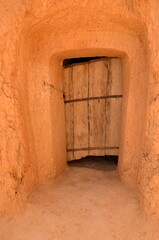 Fototapeta na wymiar Old Matmata door close up. Traditional aged wooden Tunisian door to underground houses, entrance to the cave at Matmata. Matmatat-Al-Qadimal, Tunisia, Tunisia. 06/10/2019. 